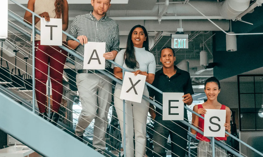 Team holding letters spelling TAXES
